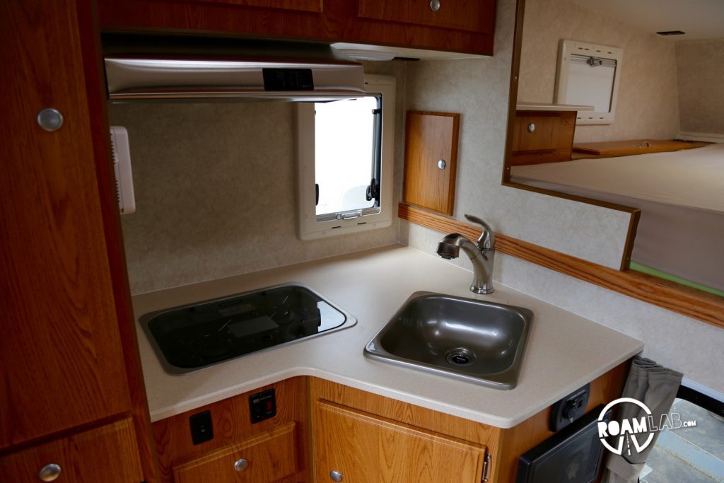 This kitchenette may be short on counter space but it does benefit from a covered stove top that is flush with the counter (left of the sink)