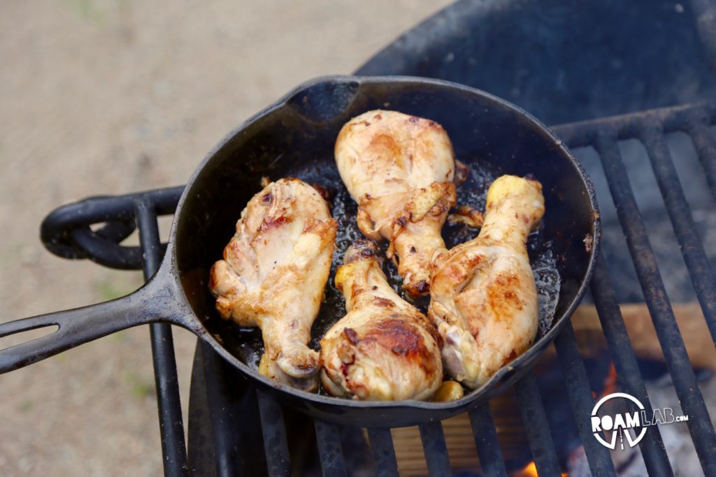 Marinaded chicken frying in a cast iron pan.