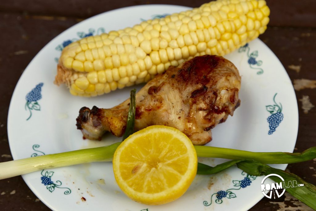 Our chicken dinner is ready with corn, green onion, and roasted lemon.