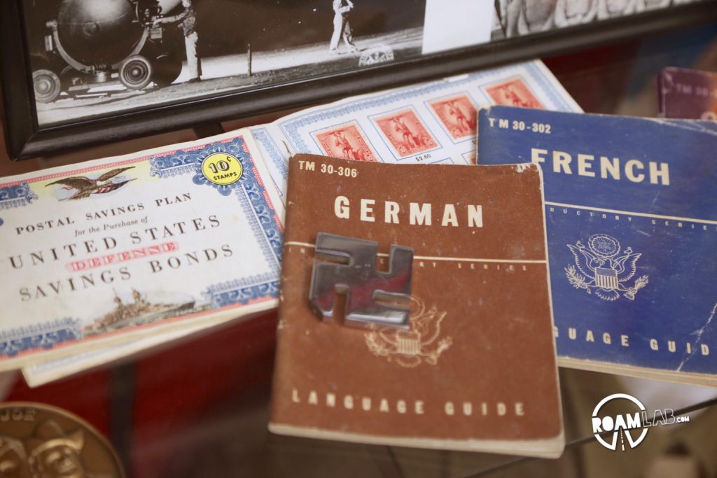 Memorabilia collected while on tour in WWII litters a wall, included mounted displays of swastikas and Nazi memorabilia much like a dears head might be mounted by a hunter.