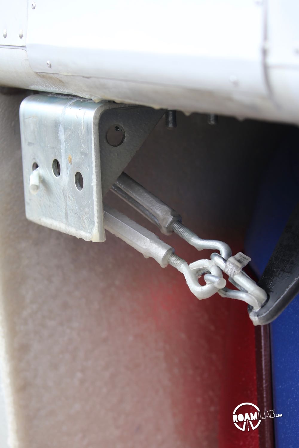 Two small turnbuckles connecting a Brophy Tie-Down and truck camper jack bracket, frozen in place.