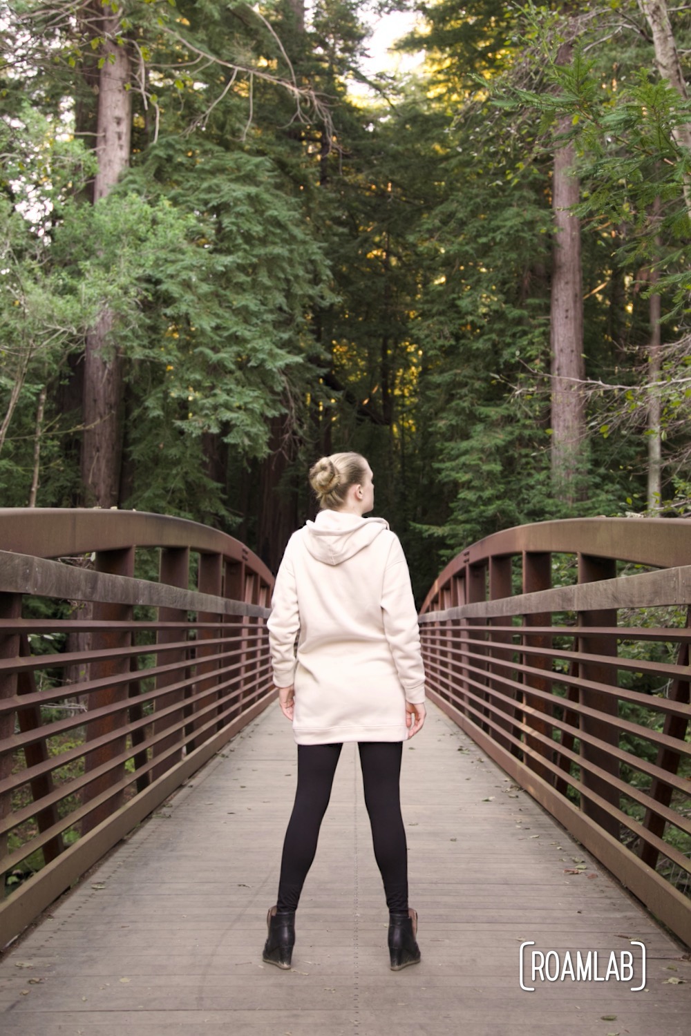 Woman standing on a bridge among the redwood trees in California's Pfeiffer Big Sur State Park.