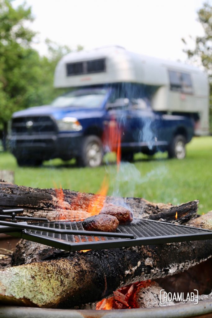 Grilling burgers outside, over a campfire on the Adjust-A-Grill.