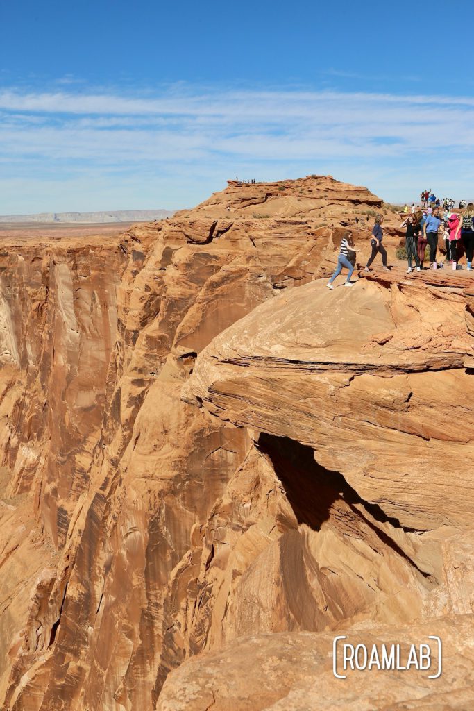 Visitors retreating after a picture on a sandstone cliff. They likely didn't see how eroded it is from their perspective.