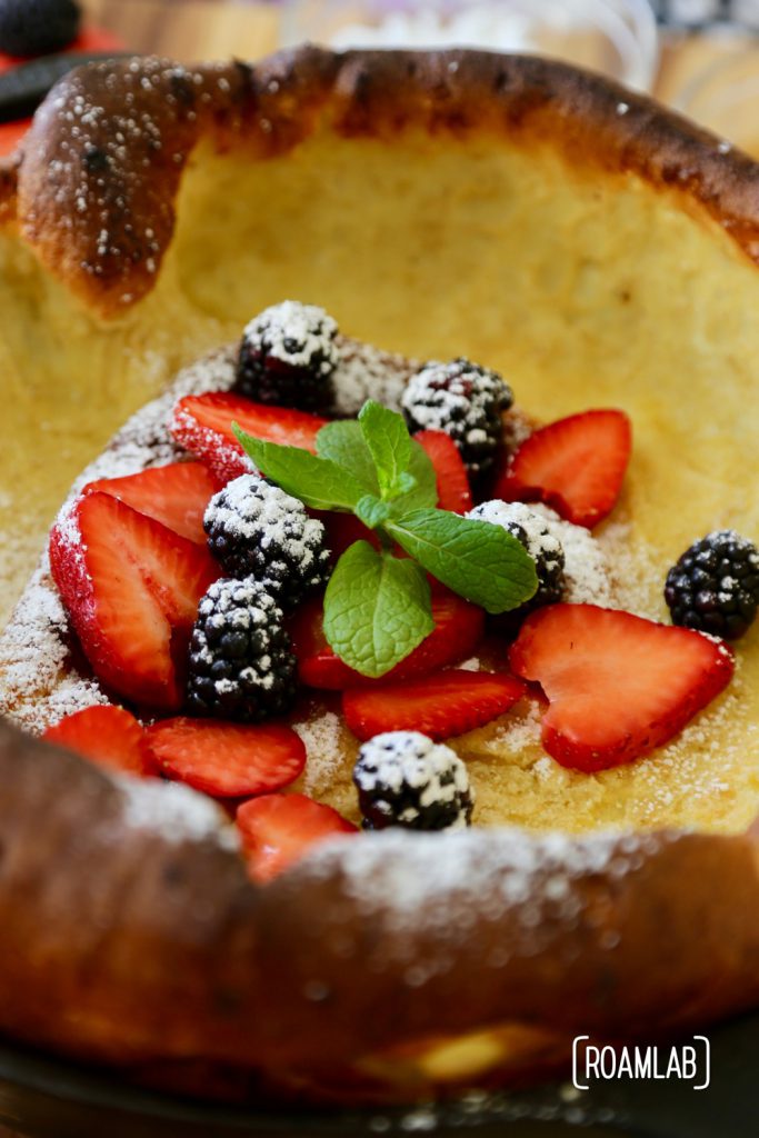 Blackberries, strawberries, powdered sugar and mint on a dutch baby pancake.
