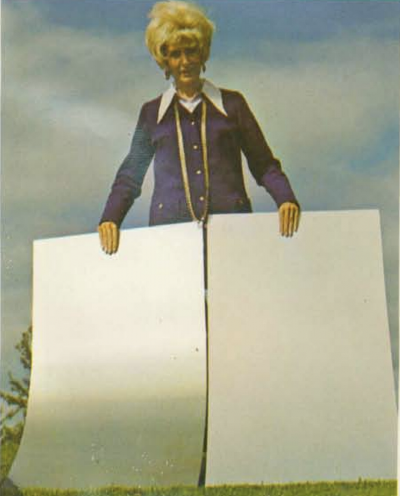 Woman holding up samples of standard aluminum sheet and anodized aluminum sheet.