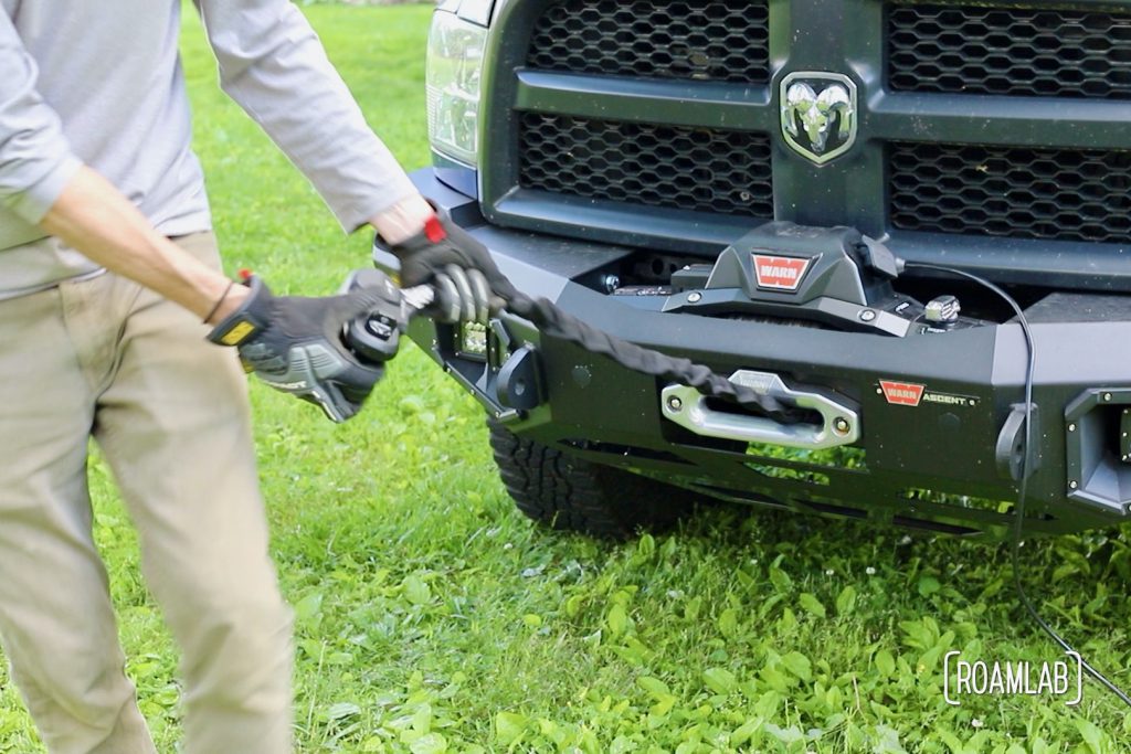 Man pulling rope out of a front bumper mounted winch.