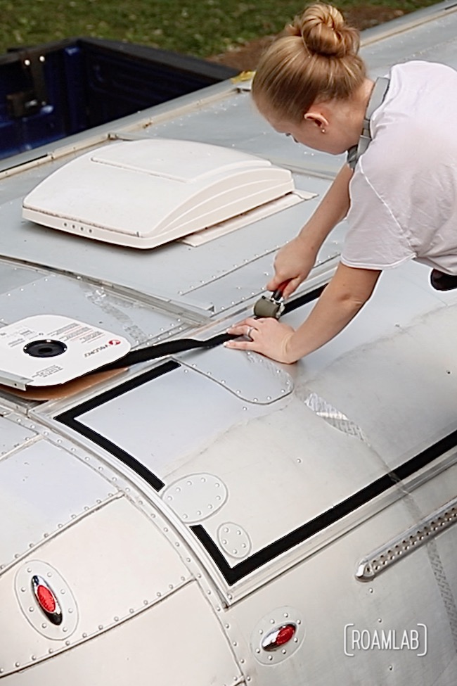 Woman applying velcro to aluminum truck camper roof.