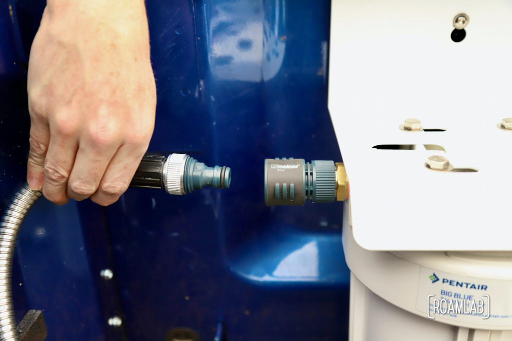 Hand inserting a quick connect hose attachment to a water filtration system.