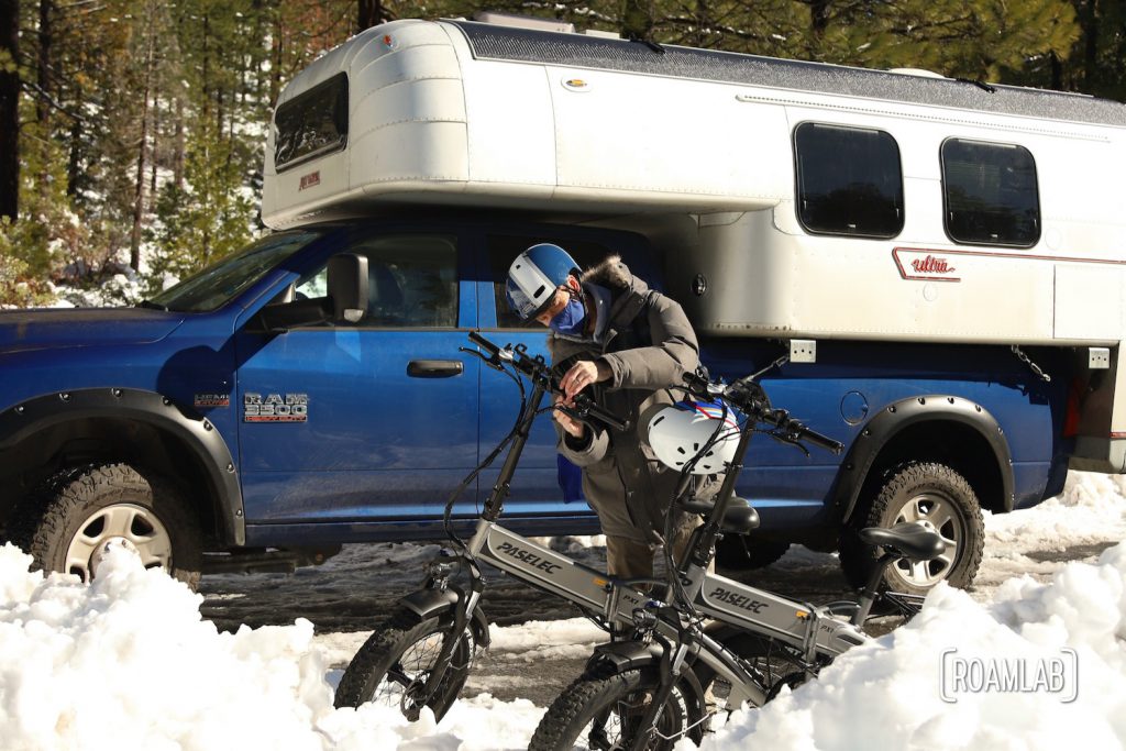 Man preparing bicycles in front of a 1970 Avion C11 truck camper.