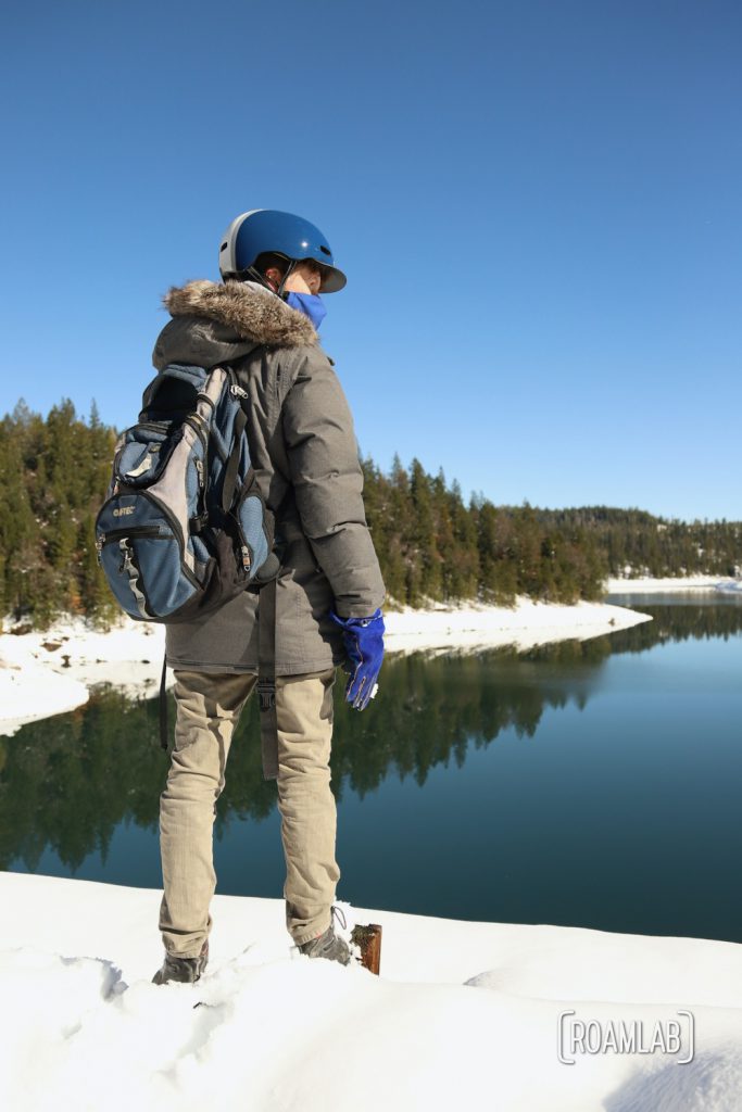 Man standing in show in front of the Sugar Pine Reservoir .