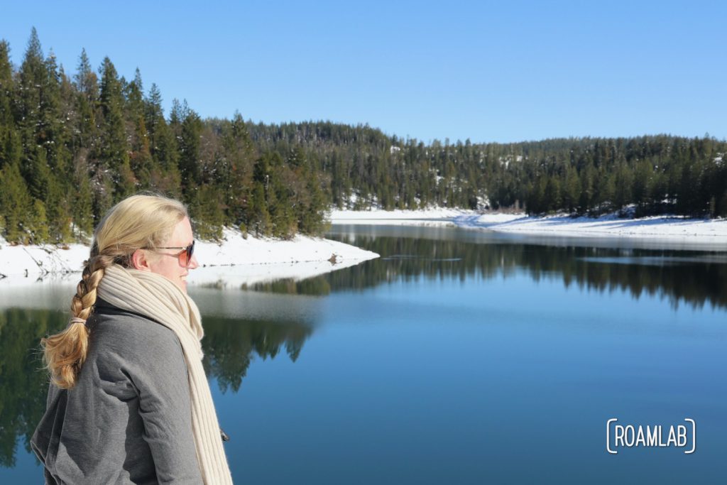 Woman looking out over the snowy shores of Sugar Pine Reservoir.