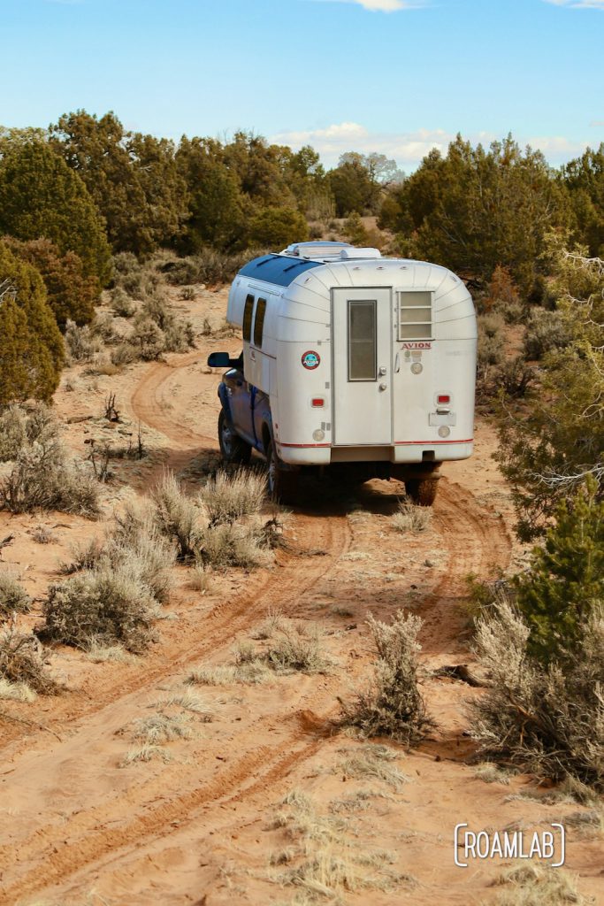 1970 Avion C11 truck camper driving up a loose pink sand trail on the way to White Pocket in the Vermillion Hills of Arizona.