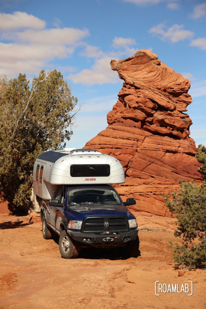 1970 Avion C11 truck camper parked next to a red rock hoodoo in Vermillion Hills National Monument.