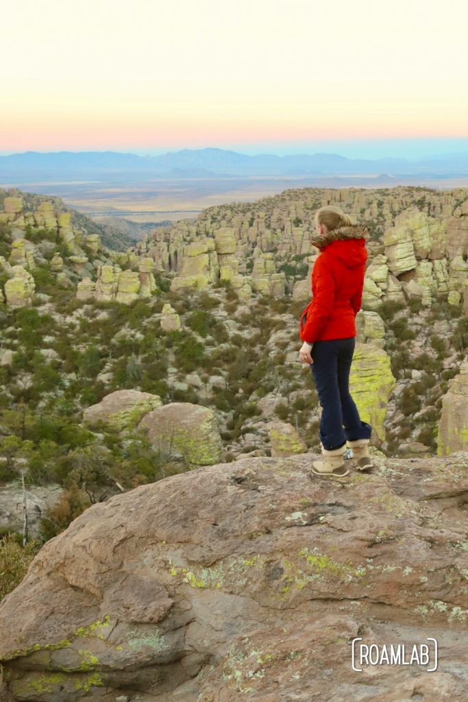 Woman looking down into a valley of hoodoos with mountains in the background on Echo Canyon Loop Trail at Chiricahua National Monument Arizona