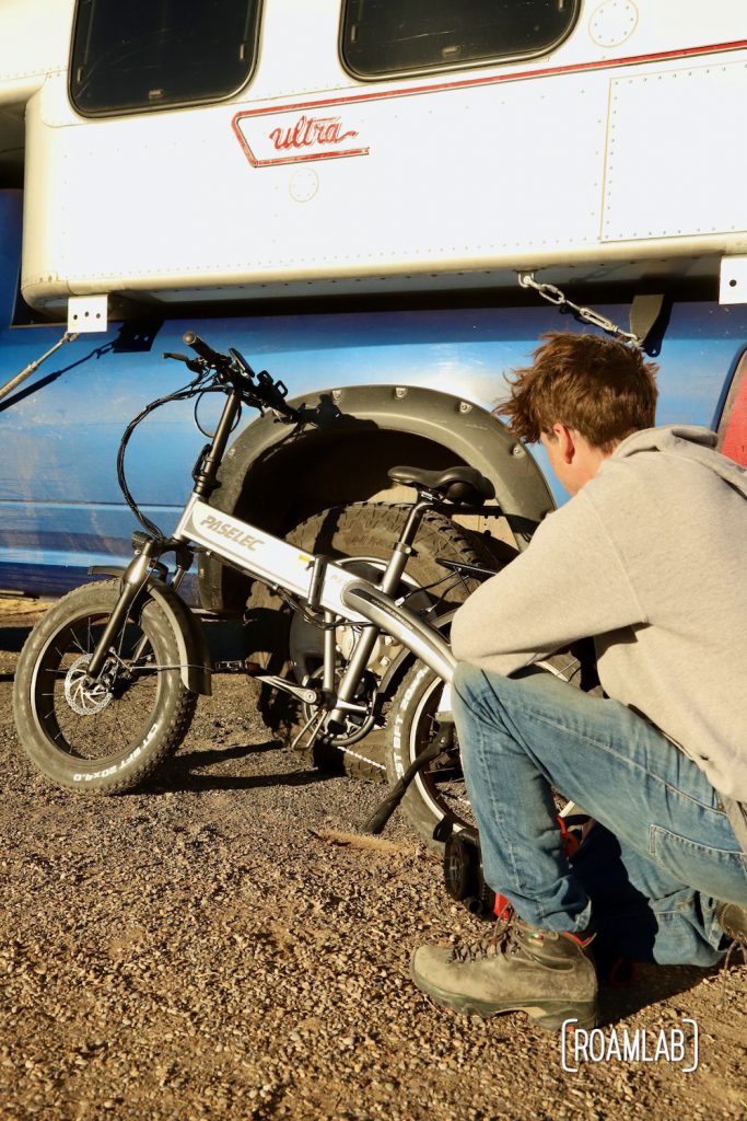 Man crouching in front of a bicycle resting on an 1970 Avion C11 truck camper.