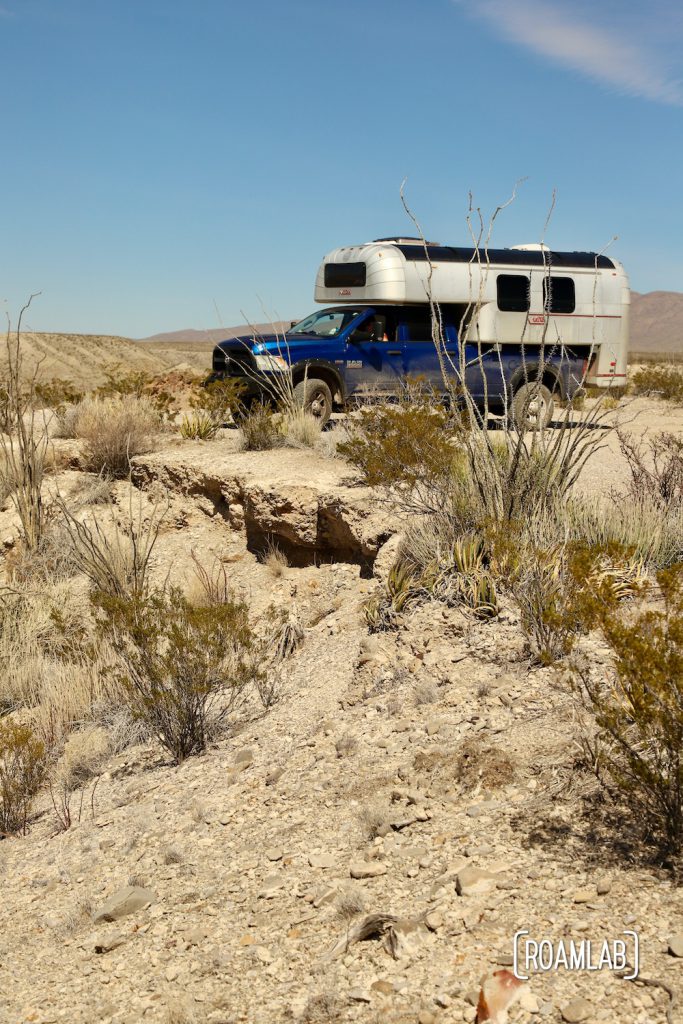 Aluminum 1970 Avion C11 truck camper on a blue truck on an overlook surrounded by desert plants along Old Ore Road in Big Bend National Park, Texas