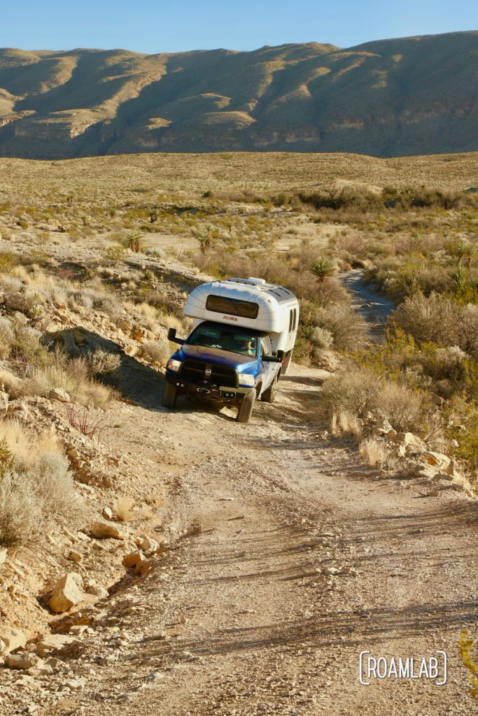 Aluminum 1970 Avion C11 truck camper on a blue Ram ascending the steep, uneven dirt Old Ore Road in Big Bend National Park, Texas