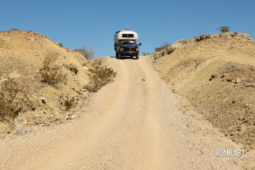 1970 Avion C11 truck camper at the top of a dirt washboard road down a hill