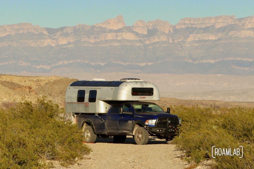 Aluminum 1970 Avion C11 truck camper parked at the end of a dirt road with mountains in the background at Fresno Campsite off River Road in Big Bend National Park, Texas.