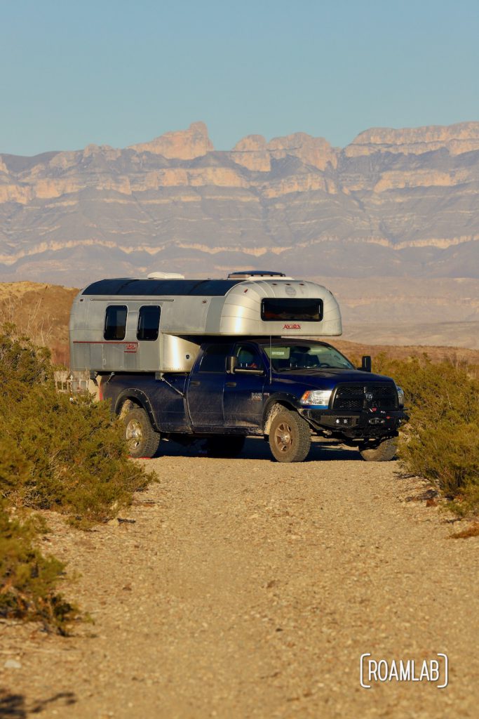 Aluminum 1970 Avion C11 truck camper parked at the end of a dirt road with mountains in the background at Fresno Campsite off River Road in Big Bend National Park, Texas.