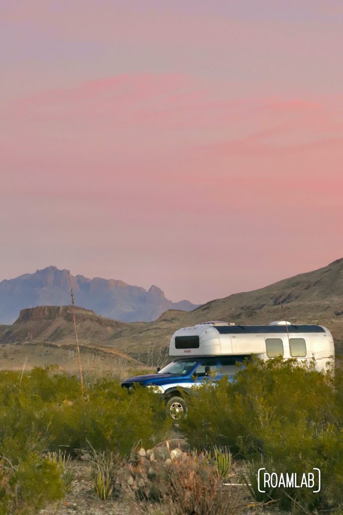 Pink sunrise skies over a 1970 Avion C11 truck camper with mountains in the background at Fresno Campsite off River Road in Big Bend National Park, Texas.