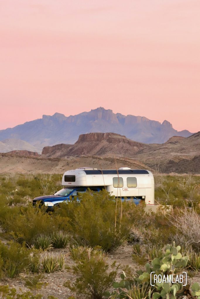Pink sunrise skies over a 1970 Avion C11 truck camper with mountains in the background at Fresno Campsite off River Road in Big Bend National Park, Texas.