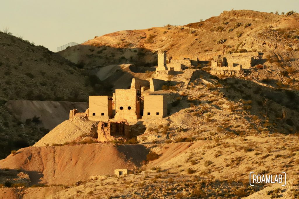 Old stone mining buildings on a desert hillside.