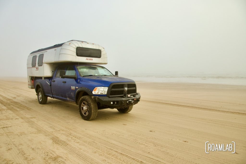 Vintage 1970 Avion C11 truck camper driving down the beach in South Padre Island, Texas