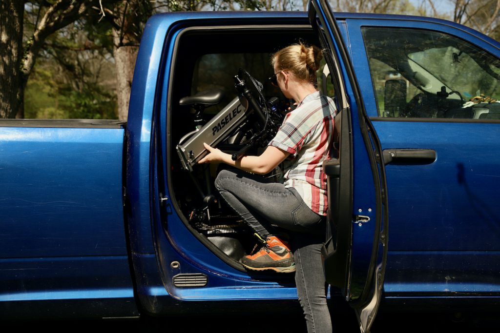 Woman lifting a folding bike into truck cab.