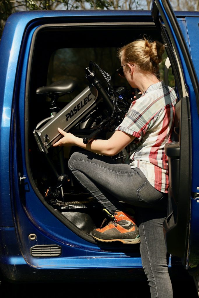 Woman lifting a folding bike into truck cab.