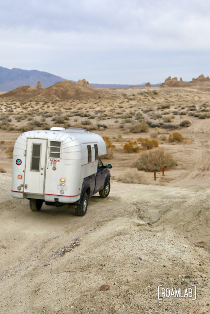 Aluminum 1970 Avion C11 truck camper driving down a dirt road in Trona Pinnacles Wilderness in south east California. 