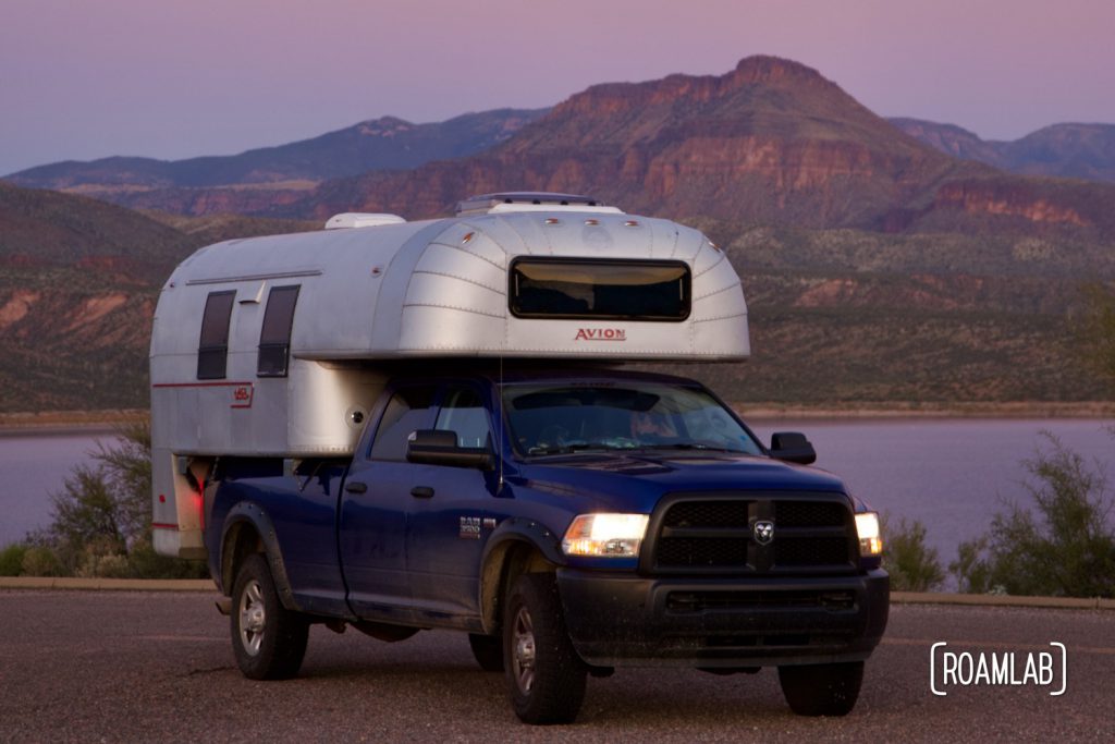 1970 Avion C11 truck camper parked at Cholla Campground with Roosevelt Lake in the background at sunset.