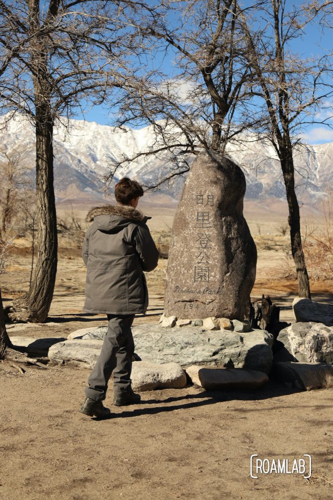 Man in heaving coat inspecting the Pleasure Park Memorial in Manzanar