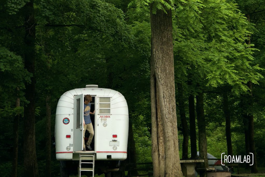 Man stepping out of a 1970 Avion C11 truck camper at Houchin Ferry Campground in Mammoth Cave National Park.