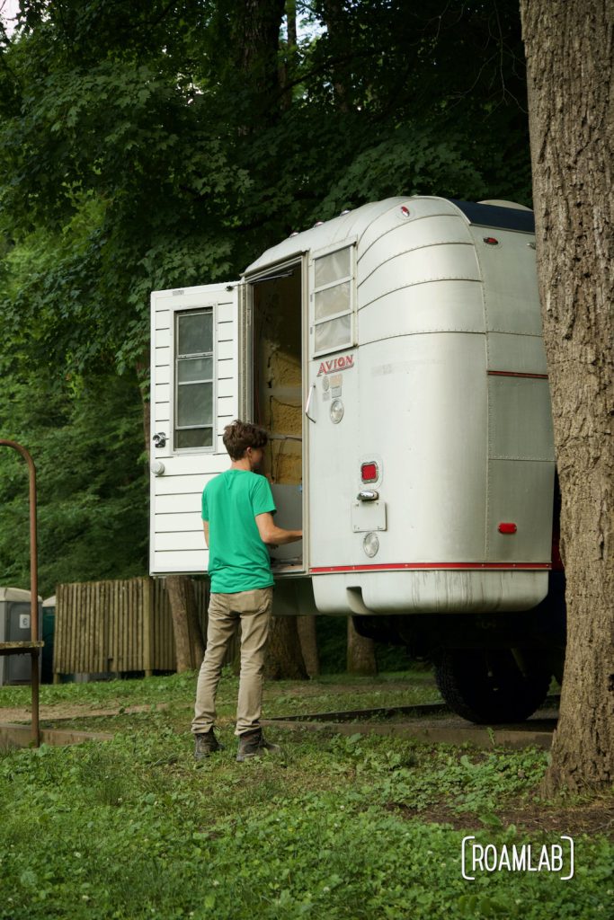 Man standing at door of a 1970 Avion C11 truck camper at the Houchin Ferry Campground in Mammoth Cave National Park.