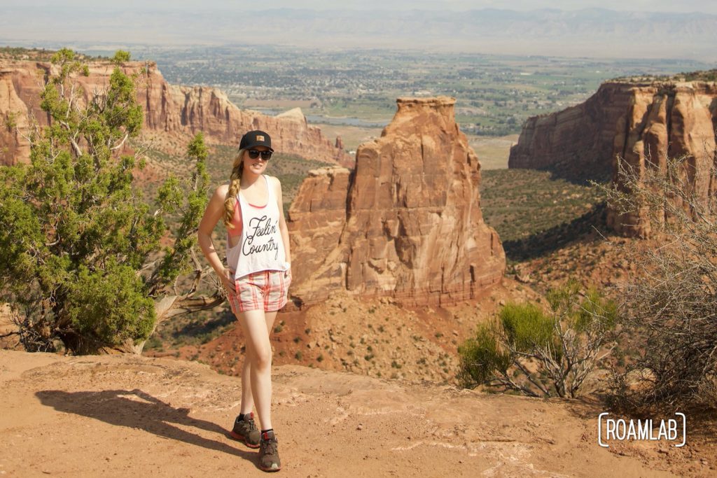 Woman walking towards camera with red rock formations in the background of Colorado National Monument.
