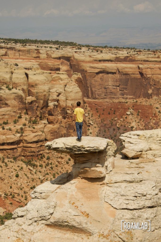 Man standing on a rock formation at Cold Shivers Point Overlook in Colorado National Monument.