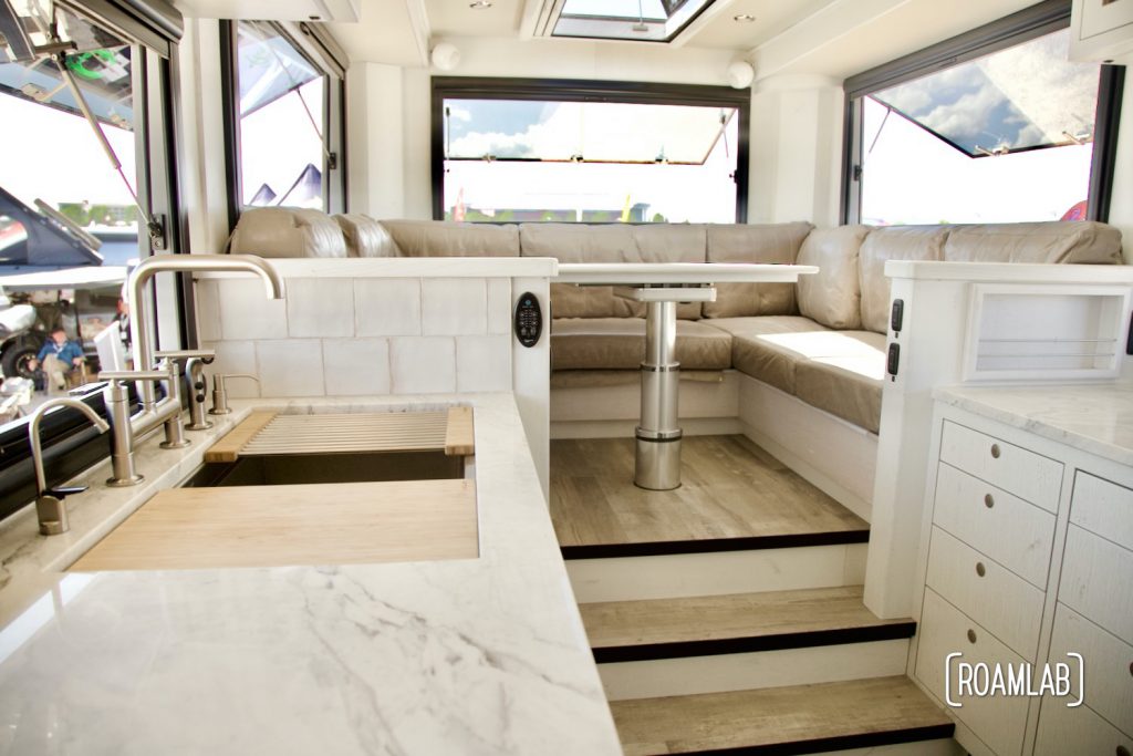Earth Roamer interior featuring a marble counter top, stainless steal fixtures, and lots of windows.