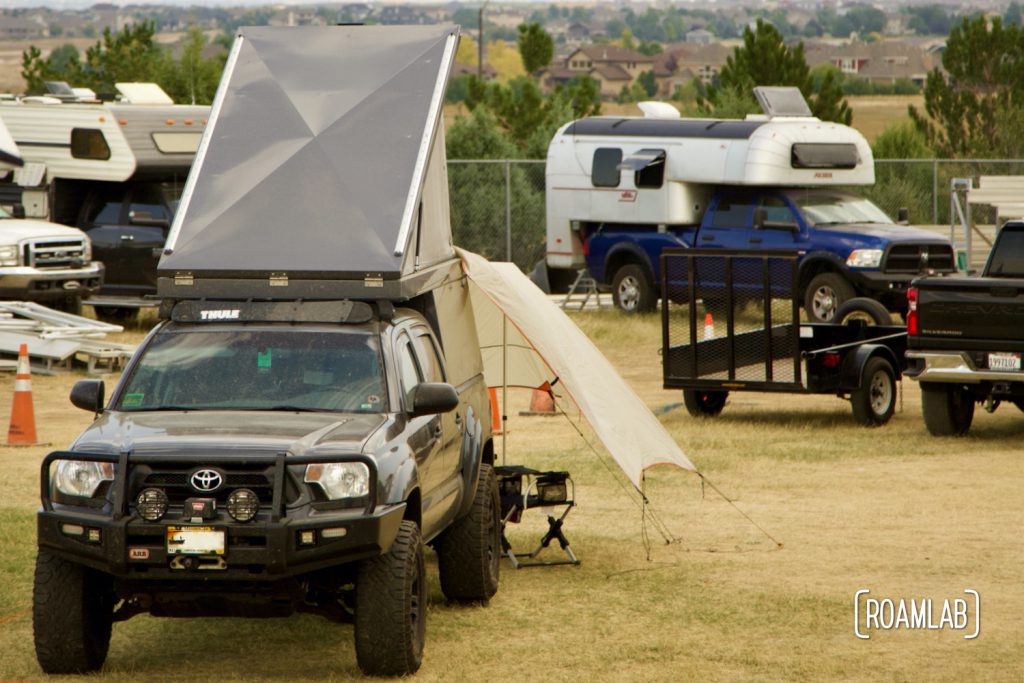 A collection of overland vehicles including truck campers and a popup roof tent camping at Overland Expo Mountain West in Loveland, Colorado.
