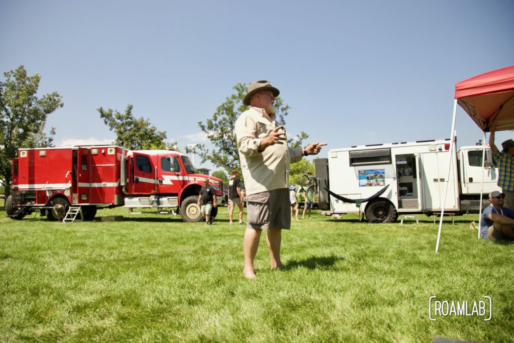 Man standing on a grassy lawn between custom overland vehicles.
