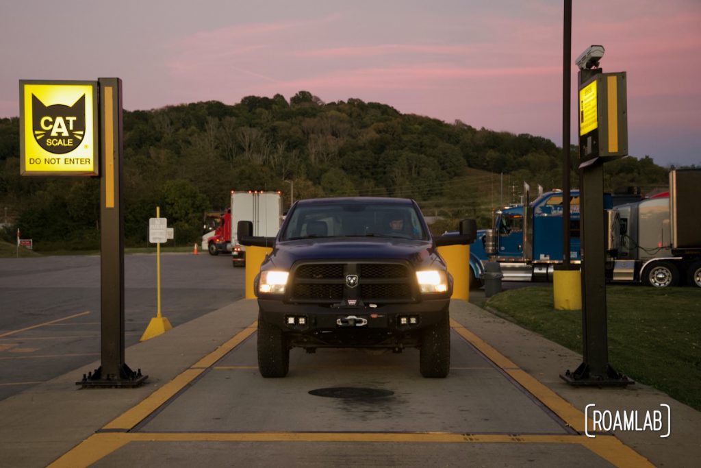 Blue 2015 Ram 3500 blue truck on a CAT Scale with sunset in the background.