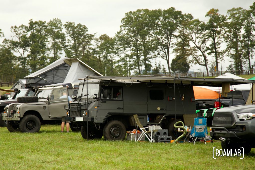 Row of refurbished military vehicles camped in a field at Overland Expo East 2021 in Arrington, Virginia.