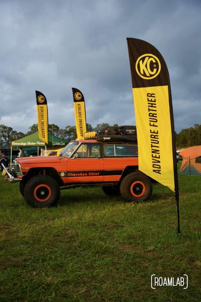 Vendor booth with bright orange rig surrounded by yellow flags for KC at Overland Expo East 2021 in Arrington, Virginia.