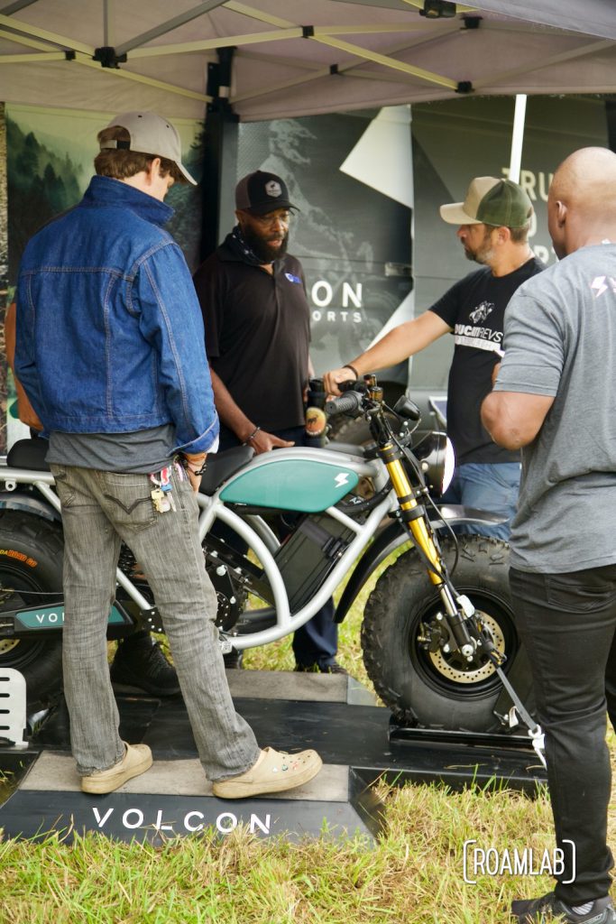 Crowd of curious attendees inspecting an electric dirt bike at Volcom's vendor booth at Overland Expo East 2021 in Arrington, Virginia.