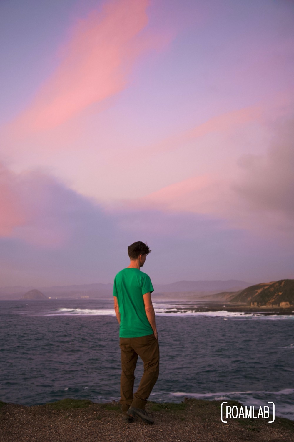 Man in a green shirt walking the coastline of Montaña de Oro State Park at sunset.