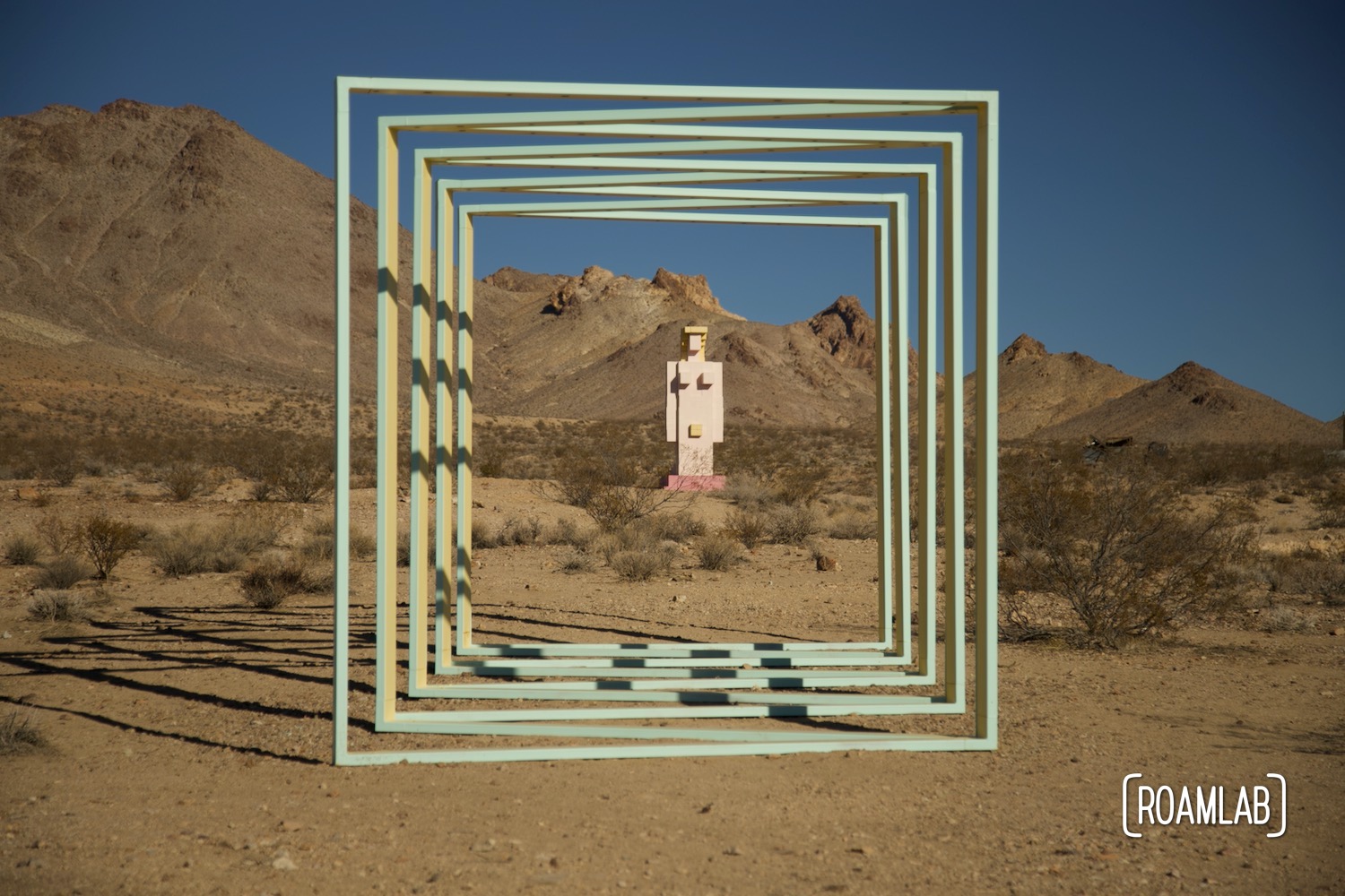 Painted steel squares zig zag on the desert floor with a pixilated cinderblock Venus in the background.