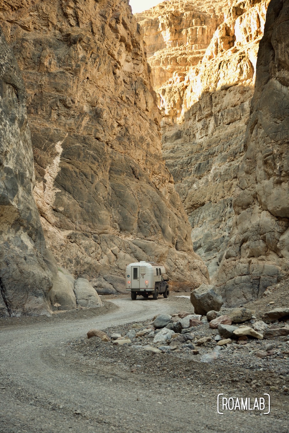 1970 Avion C11 truck camper driving through a slot canyon, following the dirt Titus Canyon Road in Death Valley National Park, California.