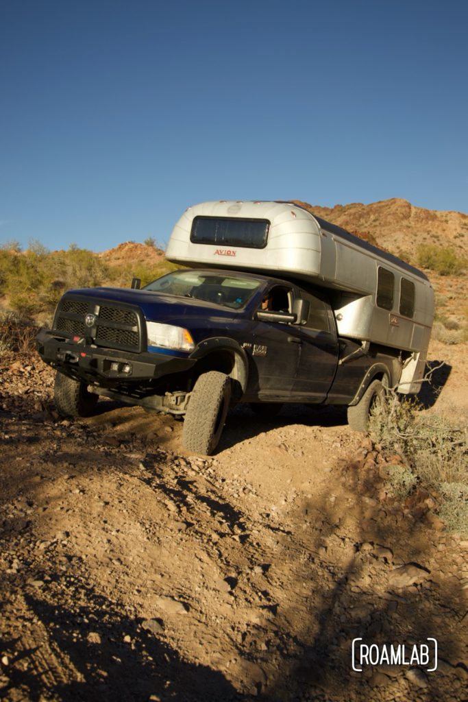 1-ton Ram truck navigating rough dirt terrain with a 1970 Avion C11 truck camper in the bed in Kofa Wilderness Refuge. 