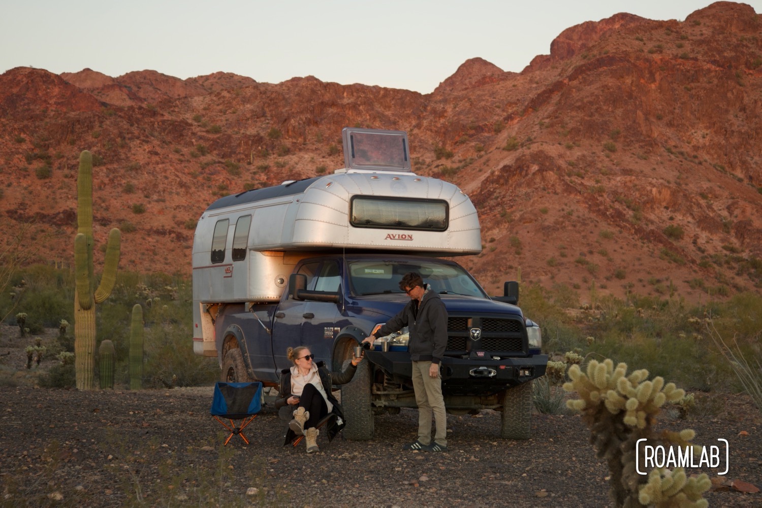 Couple sharing a bottle of beer, seated in front of a truck camper in Kofa Wilderness Refuge.